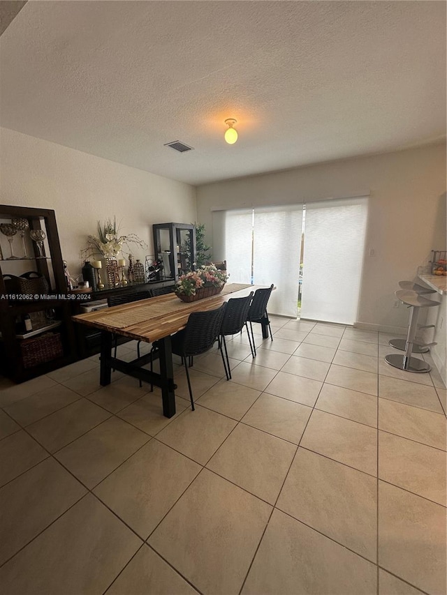 dining room featuring light tile patterned floors, visible vents, and a textured ceiling