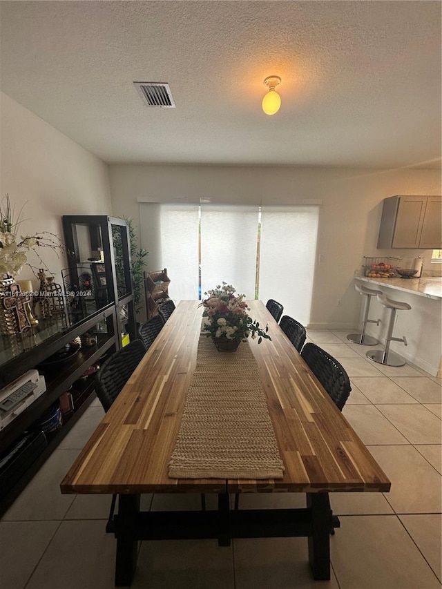 dining area featuring visible vents, a textured ceiling, and light tile patterned flooring