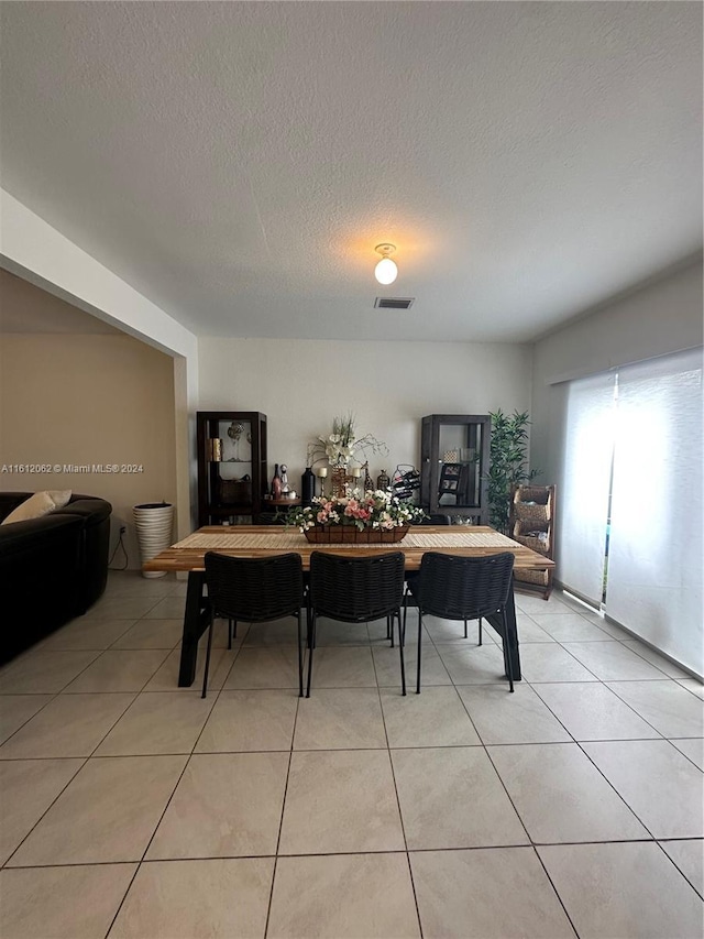 dining space featuring visible vents, a textured ceiling, and light tile patterned flooring