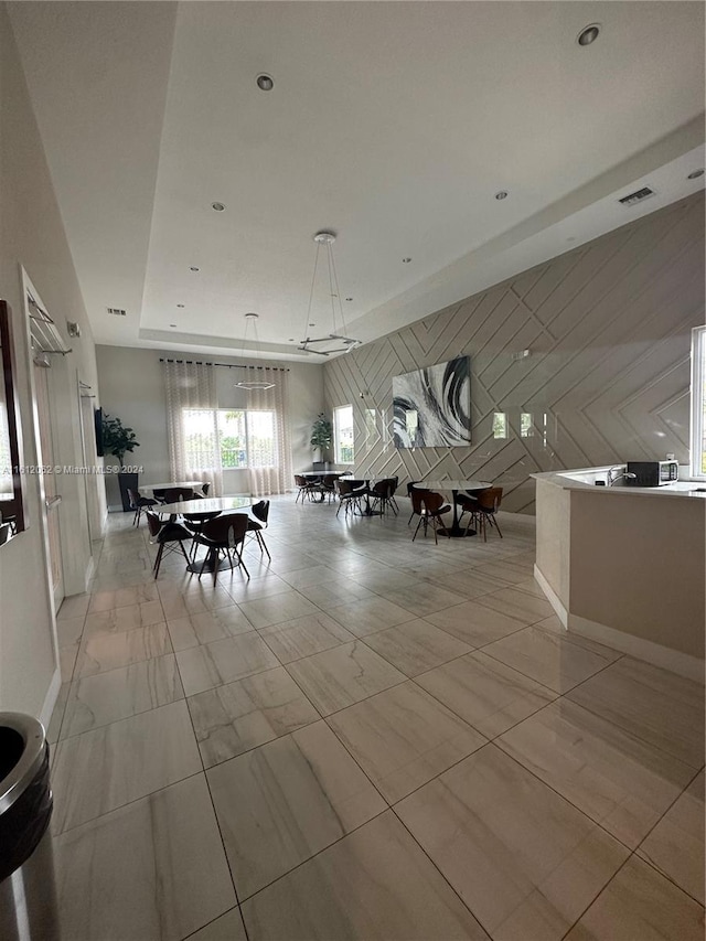 unfurnished dining area featuring a raised ceiling, wooden walls, and visible vents