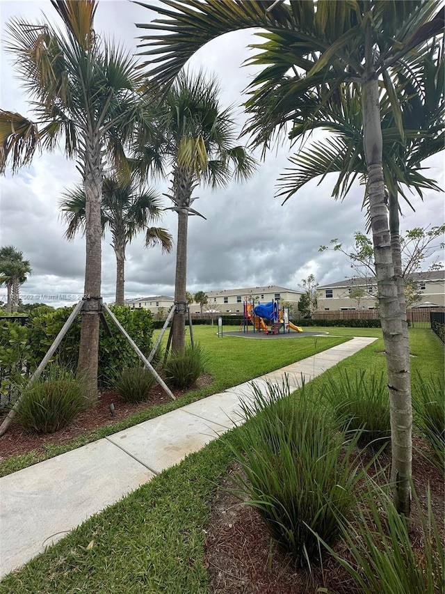 view of property's community featuring a yard, fence, and playground community