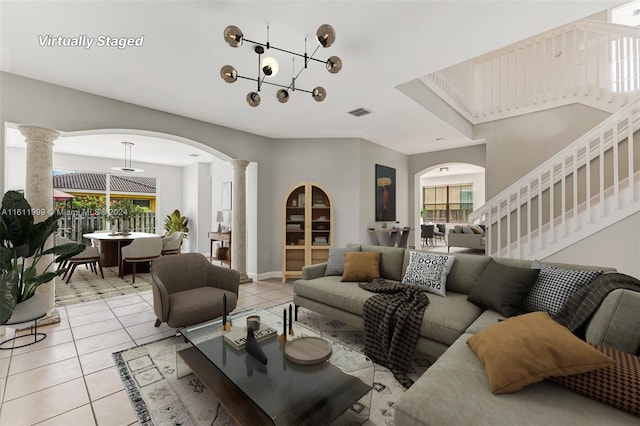 living room featuring decorative columns, light tile patterned flooring, and a healthy amount of sunlight