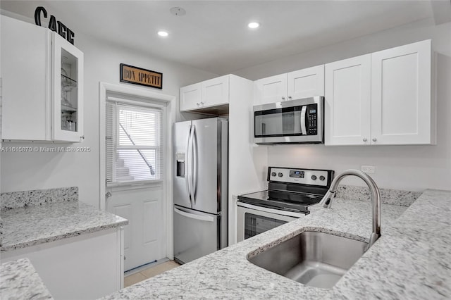 kitchen featuring sink, stainless steel appliances, white cabinetry, and light stone countertops