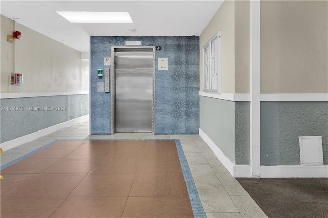 corridor featuring elevator and tile patterned floors