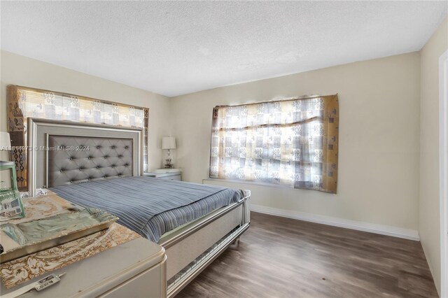 bedroom featuring a textured ceiling and dark hardwood / wood-style flooring