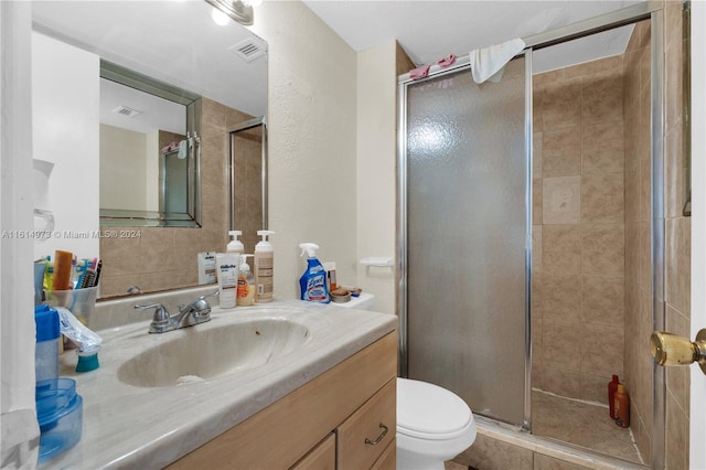 bathroom featuring vanity, toilet, and a shower with shower door