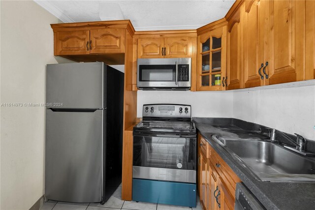 kitchen featuring sink, light tile patterned floors, appliances with stainless steel finishes, and crown molding