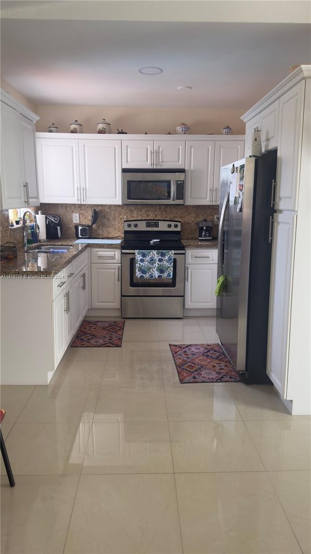 kitchen featuring light tile patterned flooring, stainless steel appliances, decorative backsplash, and white cabinetry