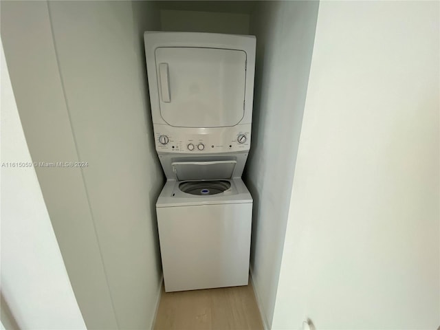 laundry area with light hardwood / wood-style floors and stacked washing maching and dryer