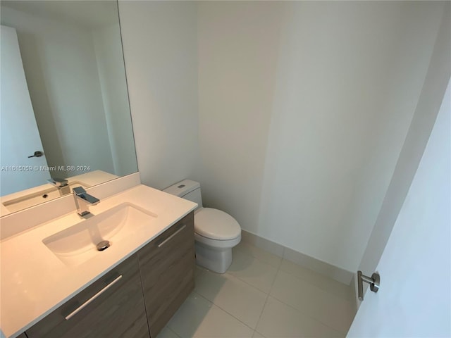 bathroom with toilet, vanity, and tile patterned flooring