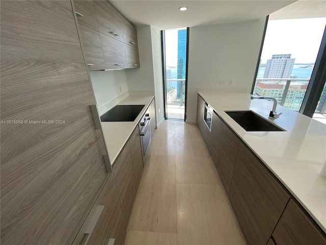 kitchen featuring sink, a wall of windows, oven, and black electric cooktop