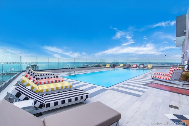 view of pool with a patio area and a water view