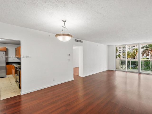 spare room with hardwood / wood-style flooring, a textured ceiling, and a wall of windows