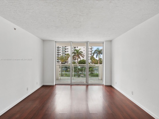 empty room featuring a wall of windows, dark wood-type flooring, and a textured ceiling