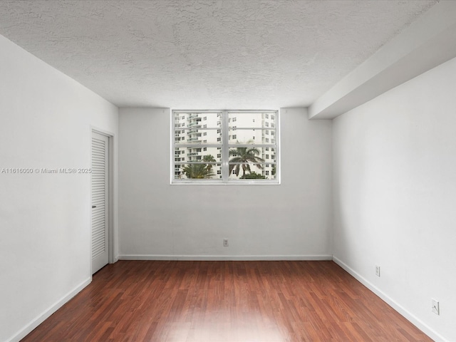 spare room with a textured ceiling and dark wood-type flooring