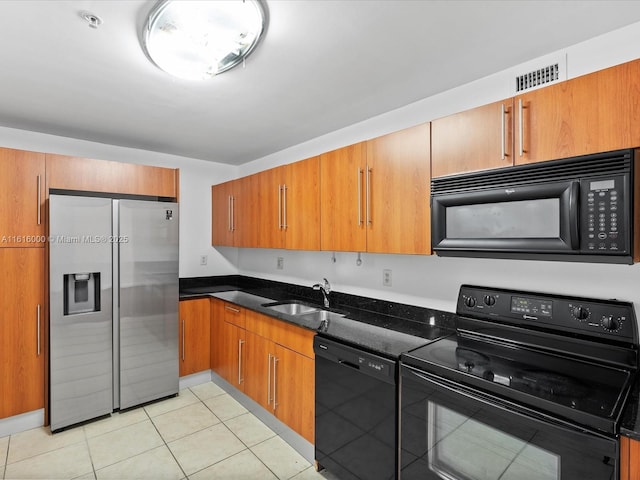 kitchen with black appliances, sink, dark stone countertops, and light tile patterned flooring