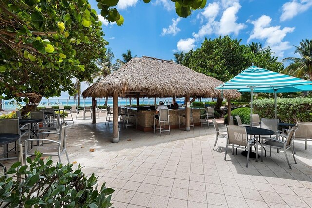 view of patio with a view of the beach, a gazebo, a water view, and exterior bar