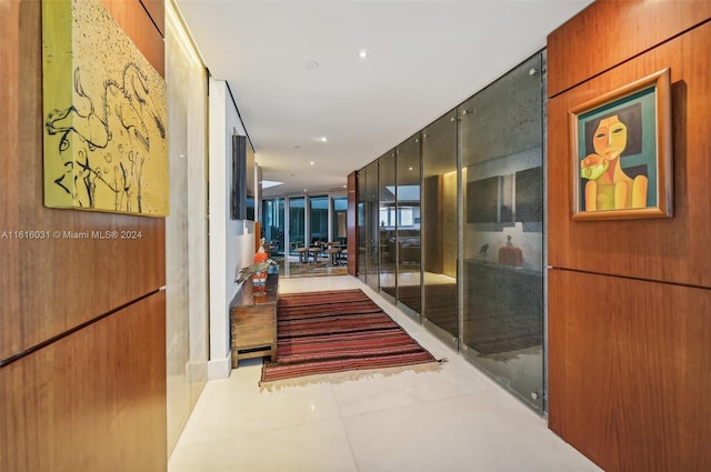 corridor featuring wood walls, light tile patterned floors, and floor to ceiling windows