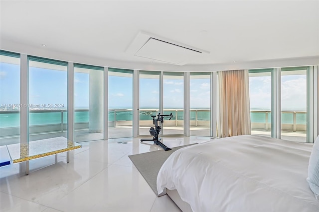 bedroom featuring a water view, floor to ceiling windows, light tile patterned floors, and access to exterior