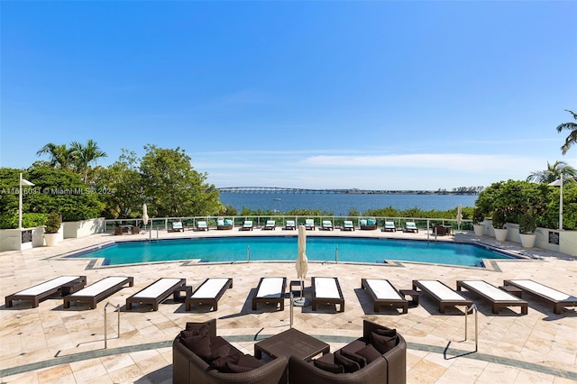 view of swimming pool featuring a patio and a water view