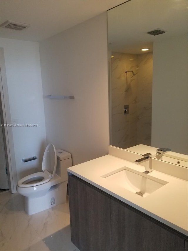 bathroom with toilet, vanity, and a tile shower