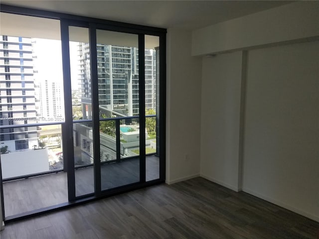 unfurnished room featuring floor to ceiling windows and dark hardwood / wood-style flooring