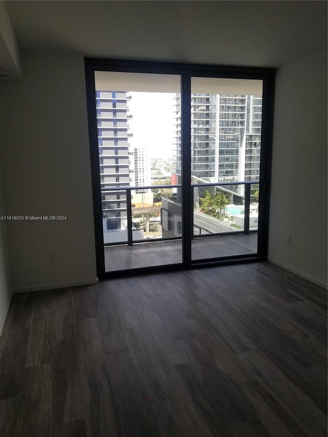 empty room with floor to ceiling windows and dark hardwood / wood-style flooring