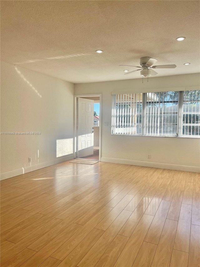 spare room featuring a textured ceiling, light hardwood / wood-style floors, and ceiling fan