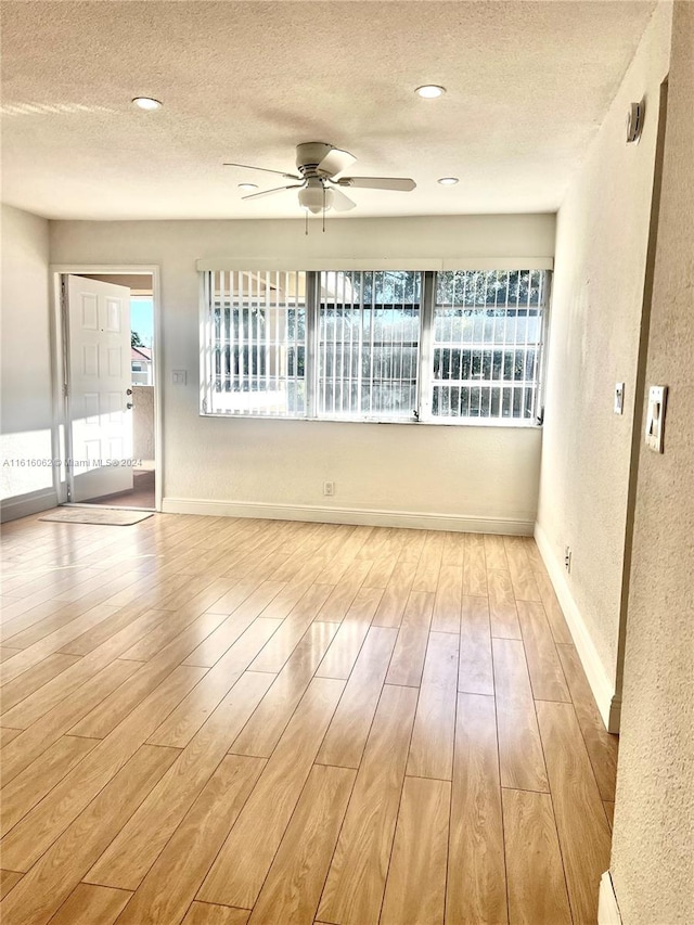 empty room with ceiling fan, a textured ceiling, and light wood-type flooring