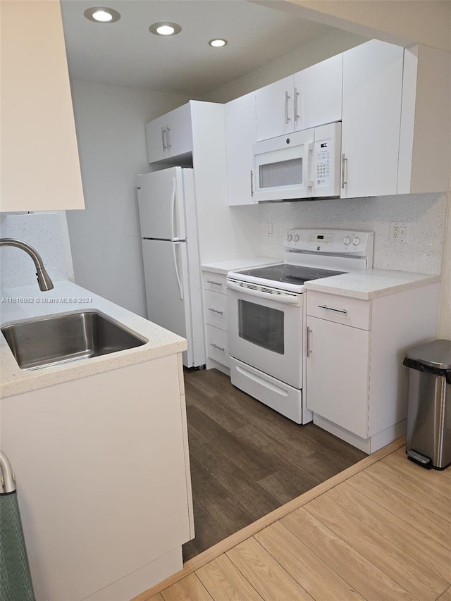 kitchen with sink, white cabinets, dark hardwood / wood-style floors, and white appliances