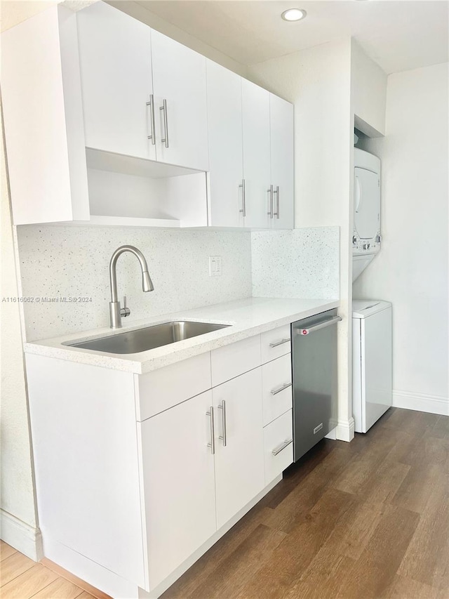 kitchen featuring stainless steel dishwasher, stacked washer / dryer, dark wood-type flooring, and sink