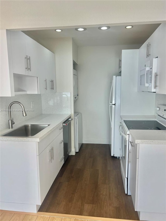 kitchen featuring white appliances, dark wood-type flooring, sink, white cabinetry, and stacked washer / drying machine