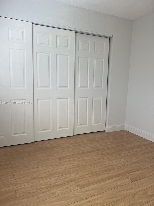 unfurnished bedroom with a closet and light hardwood / wood-style floors