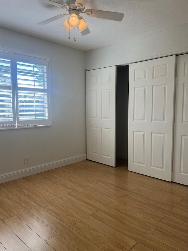 unfurnished bedroom featuring a closet, light hardwood / wood-style flooring, and ceiling fan