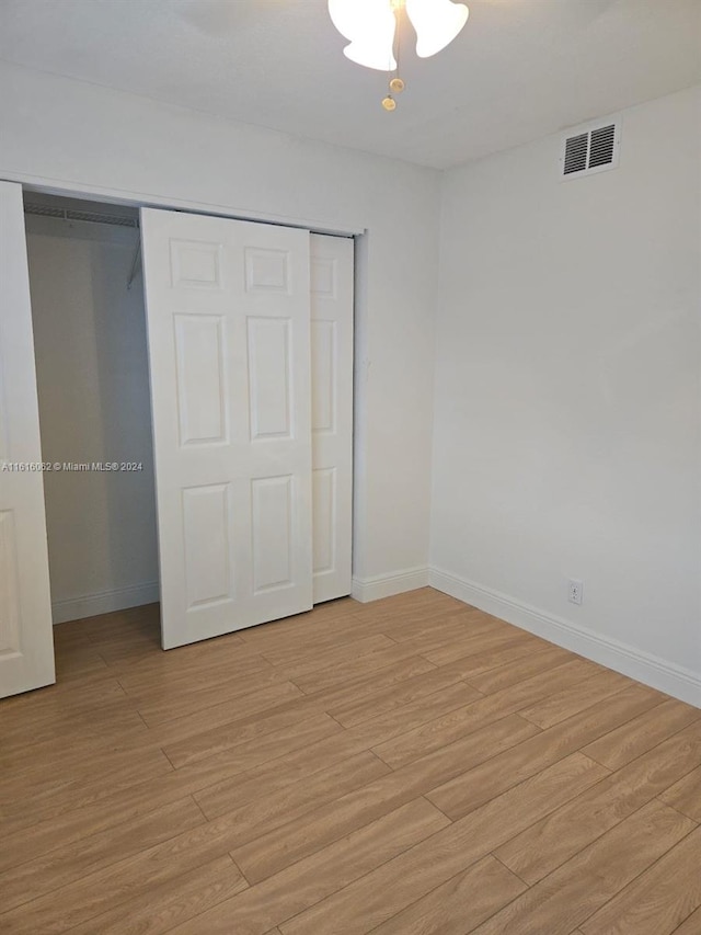 unfurnished bedroom featuring a closet, light hardwood / wood-style flooring, and ceiling fan