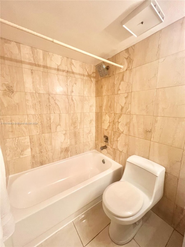 bathroom with tile patterned flooring, tiled shower / bath combo, tile walls, and toilet