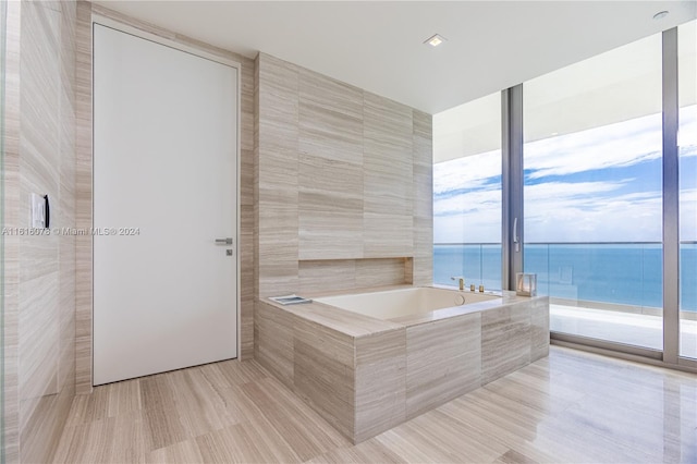 bathroom with tile patterned floors, tile walls, a water view, and tiled bath