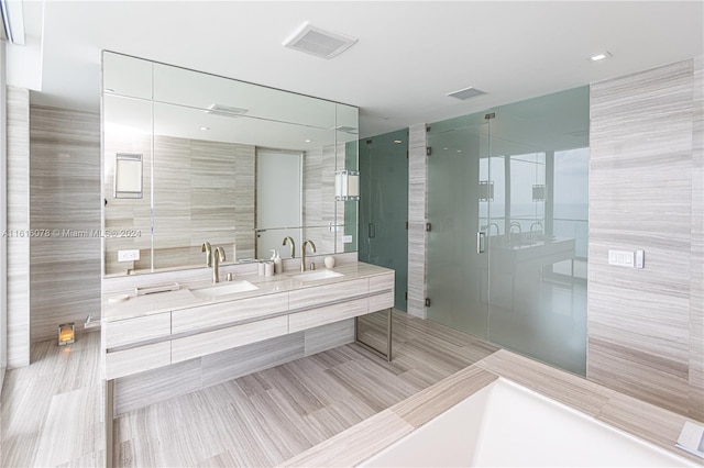 bathroom with tile walls, walk in shower, dual vanity, and tile patterned flooring