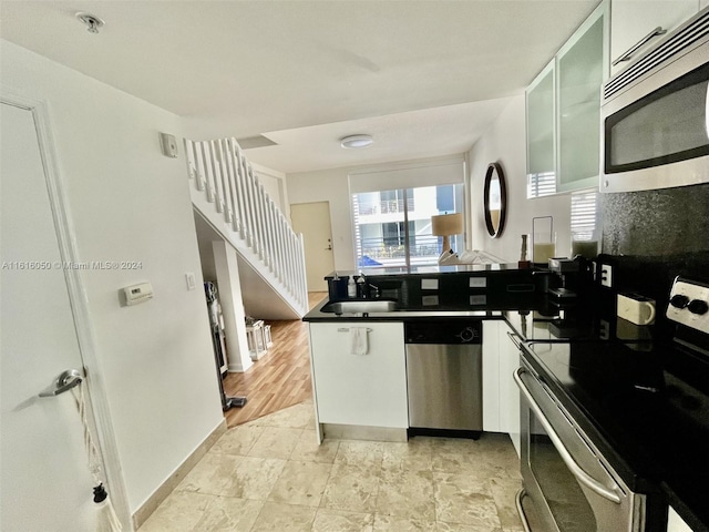 kitchen with appliances with stainless steel finishes, white cabinetry, and sink