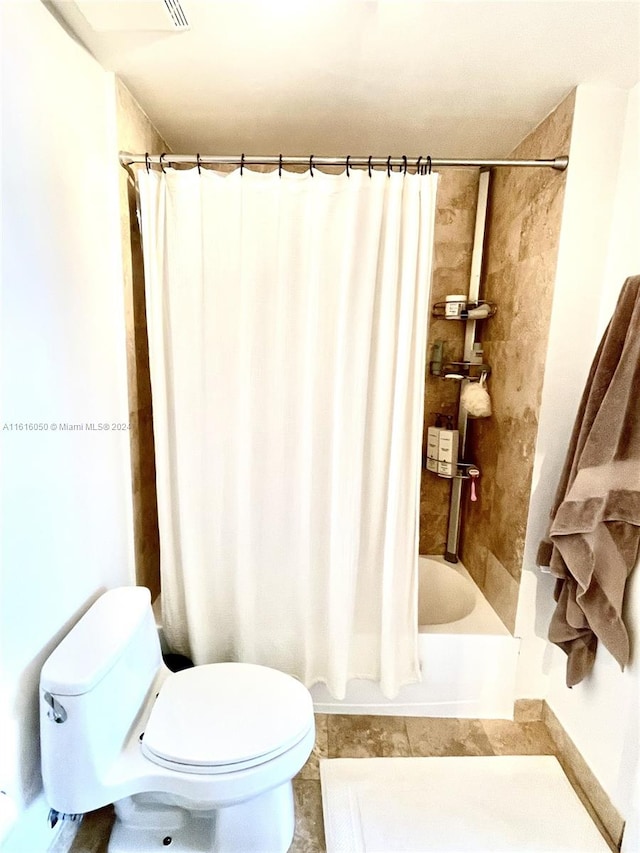 bathroom featuring tile patterned flooring, shower / tub combo with curtain, and toilet