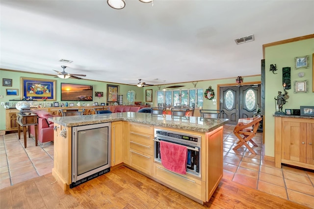 kitchen with light hardwood / wood-style floors, light brown cabinets, a center island, and stainless steel oven