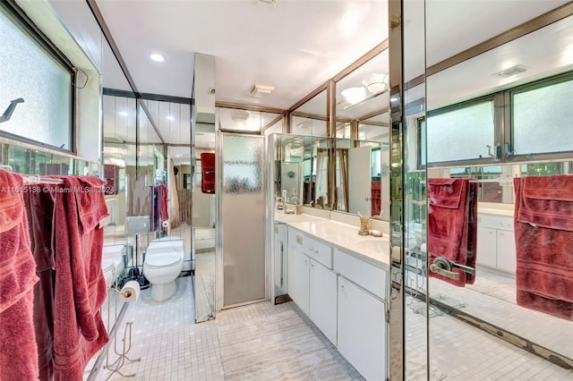 bathroom featuring toilet, a shower with shower door, vanity, and tile patterned floors