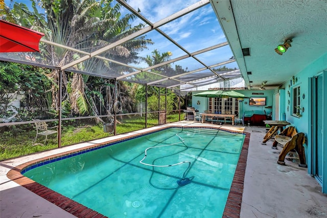 view of pool with a patio area, ceiling fan, and glass enclosure