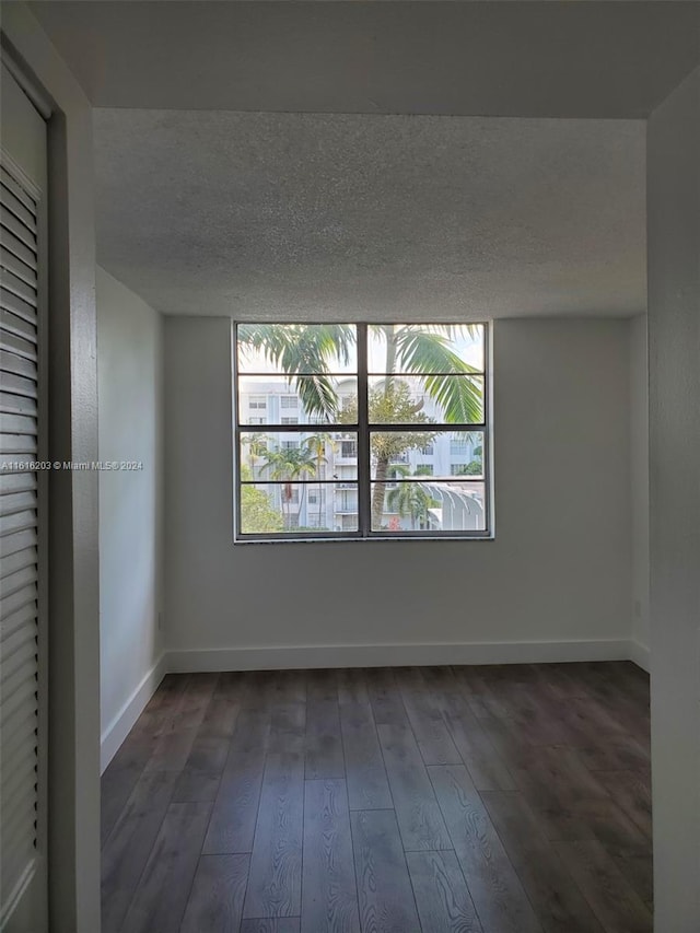 spare room with plenty of natural light, a textured ceiling, and dark hardwood / wood-style floors