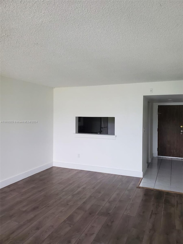 unfurnished living room with dark hardwood / wood-style floors and a textured ceiling