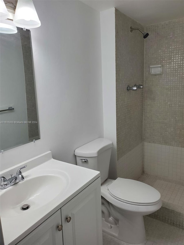 bathroom featuring toilet, vanity, and a tile shower