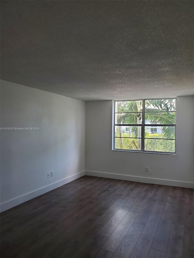 empty room featuring dark hardwood / wood-style floors and a textured ceiling