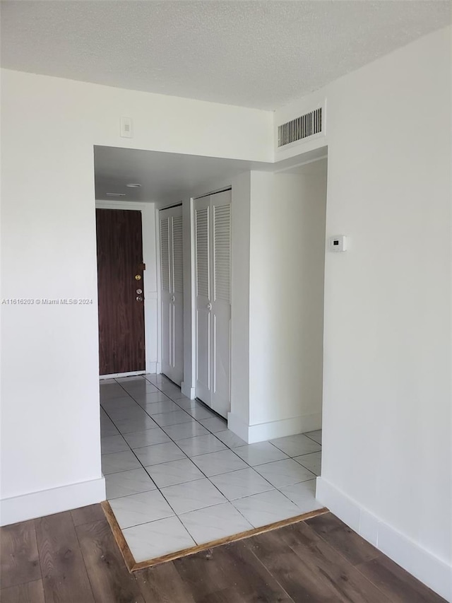 empty room with a textured ceiling and light tile patterned flooring