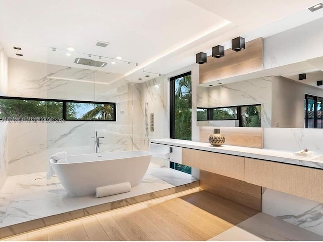 bathroom featuring vanity, wood-type flooring, shower with separate bathtub, and tile walls