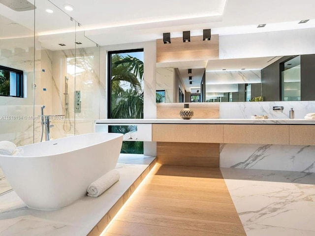 bathroom featuring vanity, tasteful backsplash, and separate shower and tub